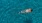 Someone swimming in a black and white bathing suit in the pool at our townhomes in Santa Palo Verde, CA, as seen from above.